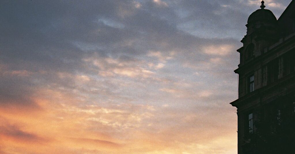 夕暮れ時の幻想的なヨーロッパ風の屋敷。窓から温かな光が漏れる、雰囲気のある情景。