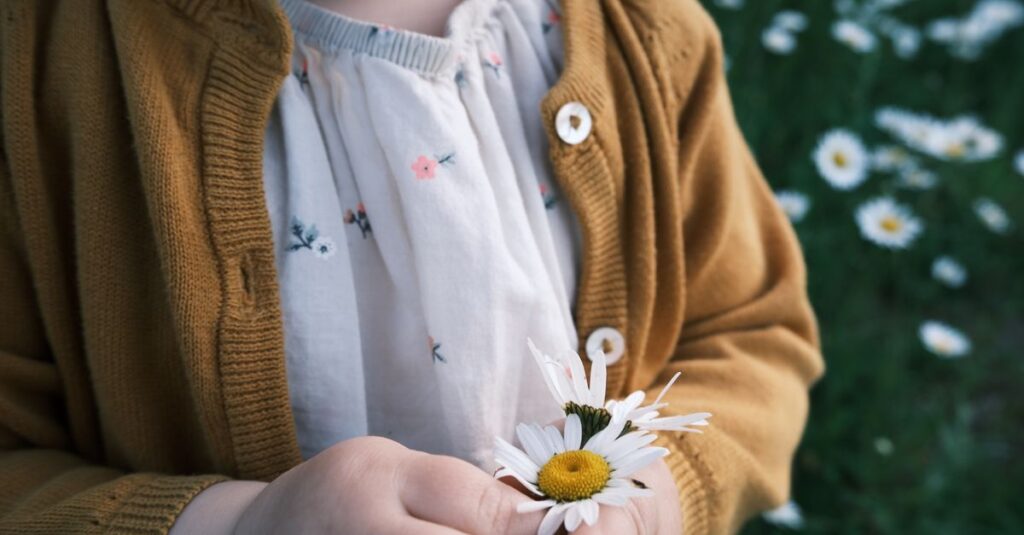 差し出された花をそっと受け取ろうとする子供。おそるおそる、でも希望の灯る表情。