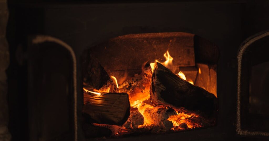 石造りの部屋で小さな暖炉の世話をする女性。守り、育てる温かなエネルギー。ろうそくの灯りが揺れる。