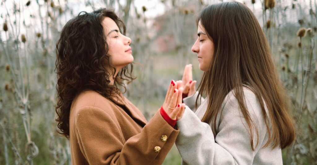 静かな庭で手を取り合うふたりの女性。一方は心配そうに、もう一方は決意の表情で。午後の柔らかな光の中。