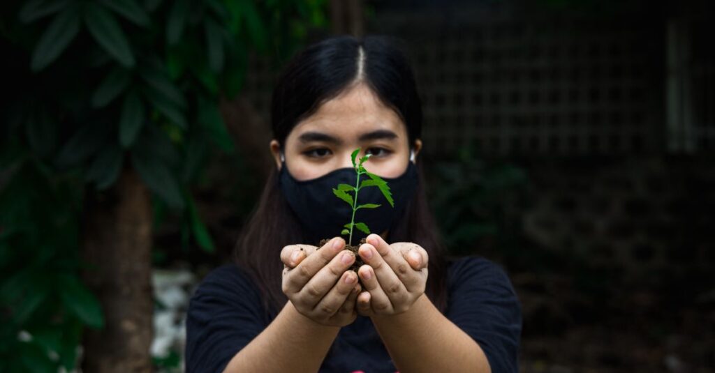 庭にひざをつき、両手で丁寧に苗を植える女性。その表情には決意と希望が宿っている。