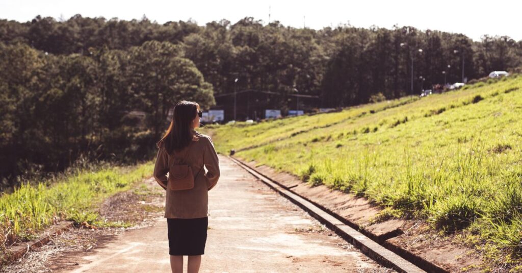 細い石畳の道をひとりで前に進む女性。背中に小さな荷物を背負いながら、振り返らずただ前を向いている。静かな気品がある。