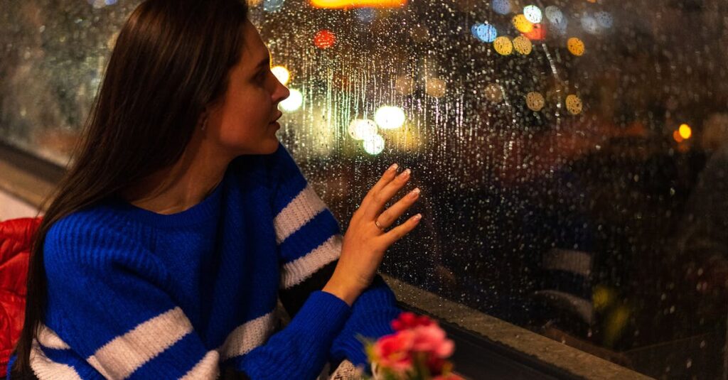 雨の窓辺でひとり静かに座る人。過去と静かに向き合う、やわらかな時間。