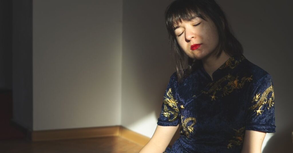 薄暗い部屋でひざを抱える女性。誰にも言えなかった孤独が、静かに積もる。