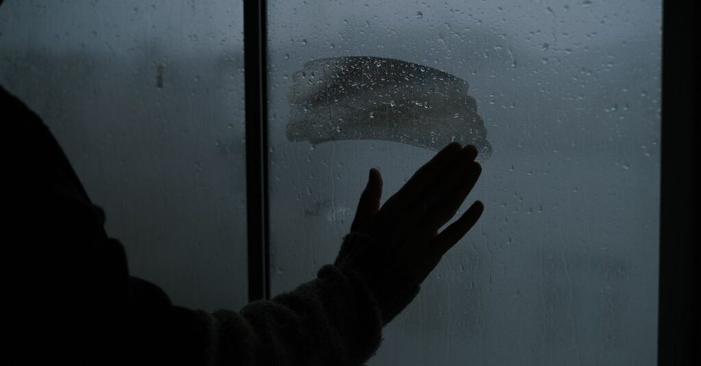 雨の窓辺でひとり静かに座る人。過去と静かに向き合う、やわらかな時間。