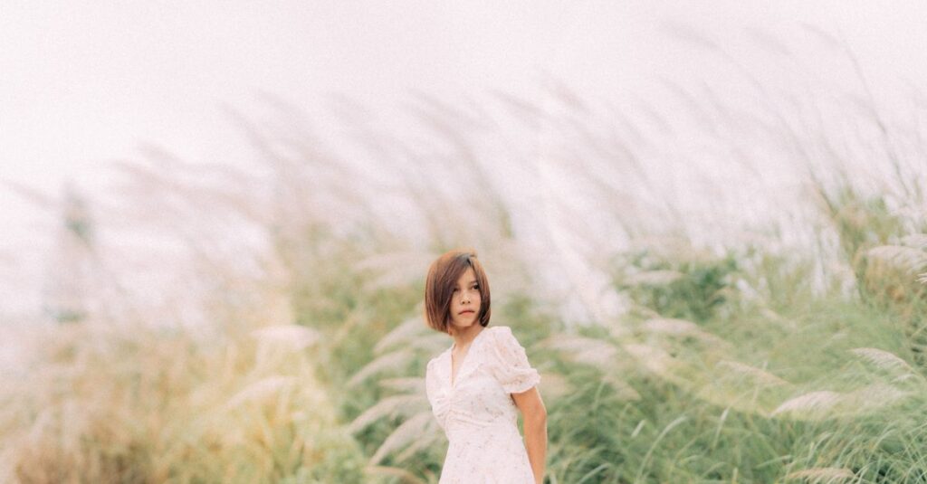 やわらかな風の中で静かに立つ女性。弱さを抱えながらも、凛と立つ姿。