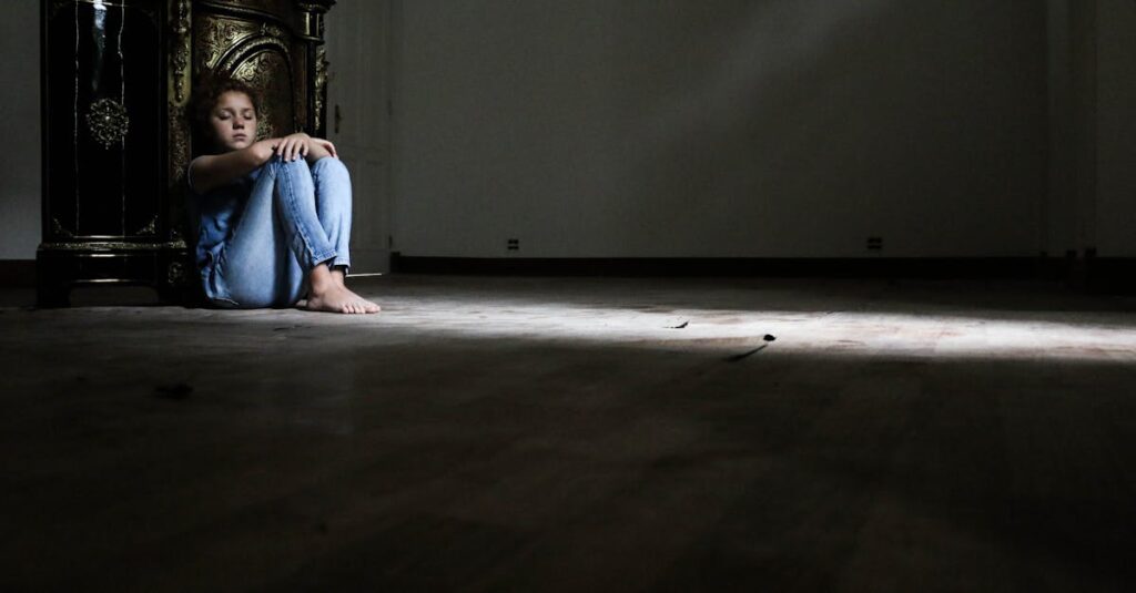 薄暗い部屋でひざを抱える女性。誰にも言えなかった孤独が、静かに積もる。