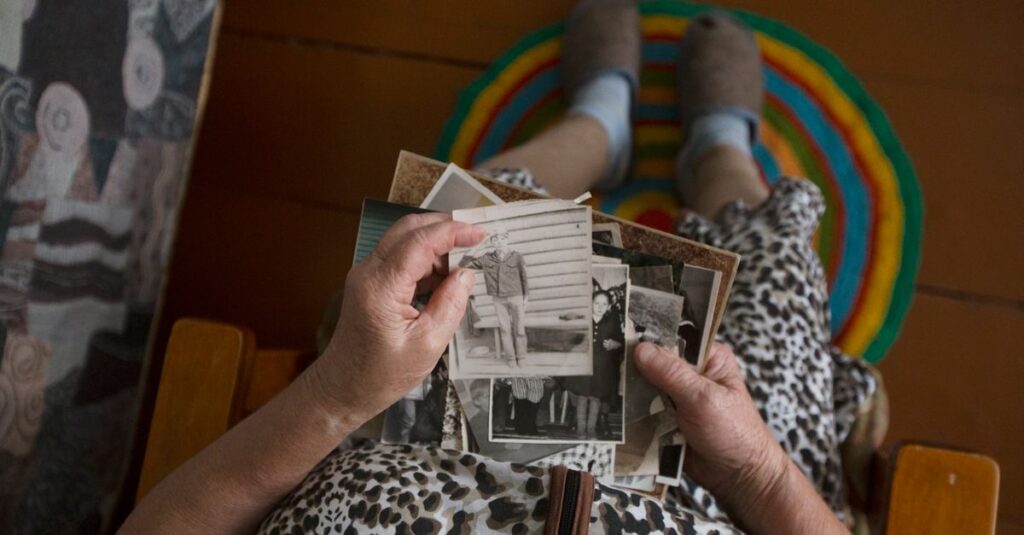 古い写真をそっと手に取る女性。過去を受け入れ、静かに前を向く姿。