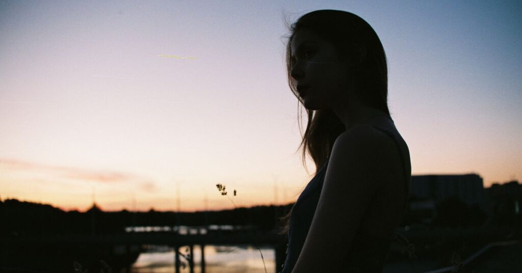 夕暮れの光の中で静かに微笑む女の子。孤独と共存することを、少しだけ受け入れた表情。