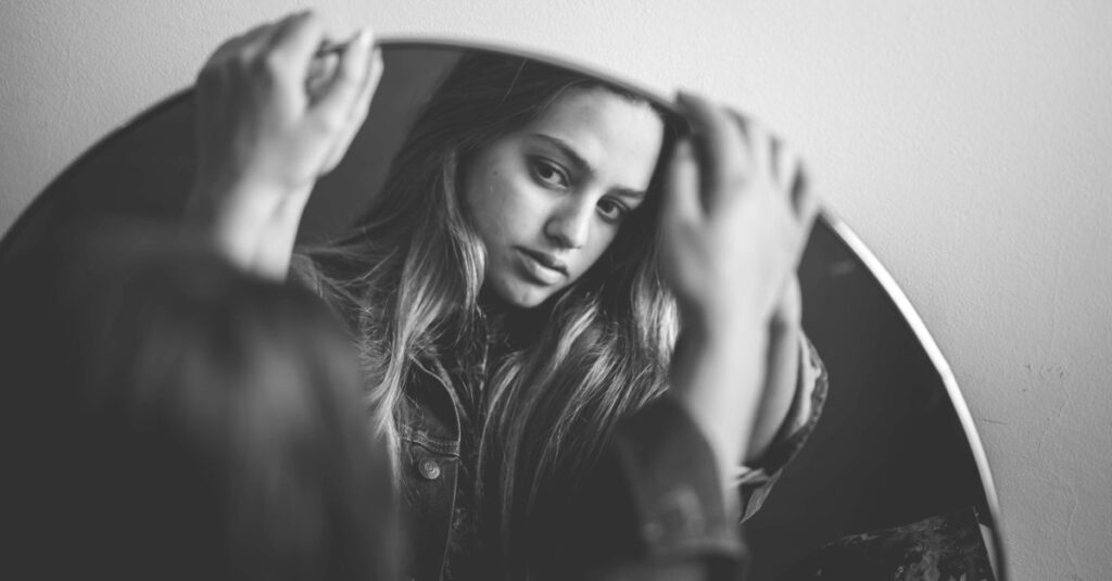 鏡の前で静かに自分と向き合う女性。「自分はどうしたいか」を問い直す、静かな時間。