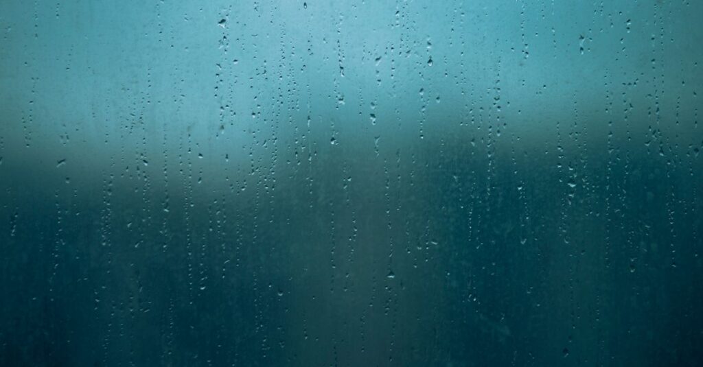 雨の日の窓辺で涙する女性。溜めてきた感情がそっとあふれる瞬間を象徴する風景。
