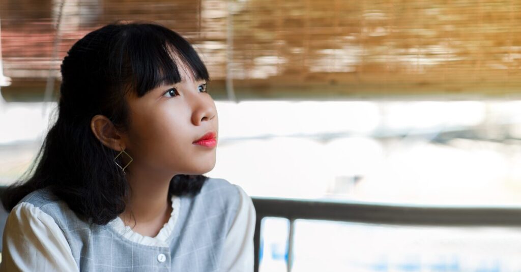 少し考え込みながらもやわらかく微笑む女性。自分の本音に気づき始めた穏やかな時間を象徴する情景。