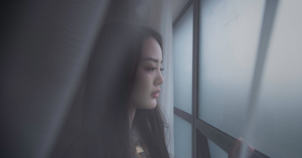 雨の日の窓辺で涙する女性。溜めてきた感情がそっとあふれる瞬間を象徴する風景。