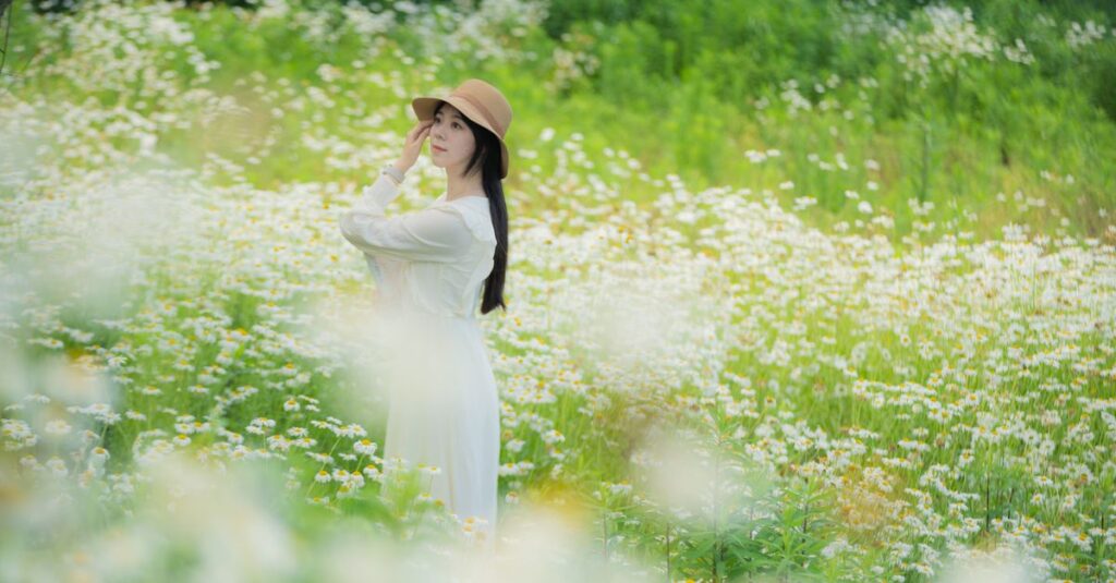 小道の脇でゆっくり花を摘む女性。急がない旅の穏やかな豊かさを象徴する風景。