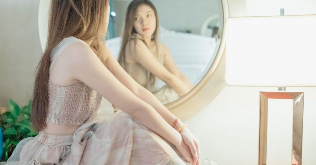 鏡の前で静かに自分を見つめる女性。自分が自分を監視していたことへの気づきを象徴する風景。