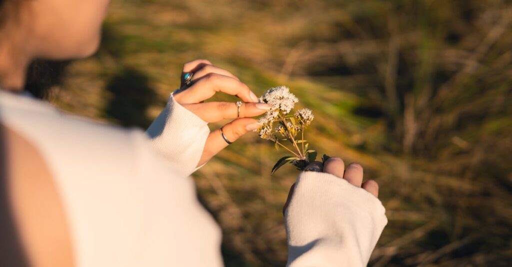 小道の脇でゆっくり花を摘む女性。急がない旅の穏やかな豊かさを象徴する風景。