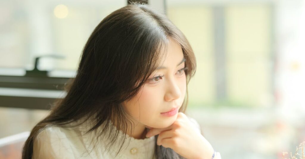 夜の街の光をひとり見つめる女性。未来の不安と静かに向き合いながら、自分の心の声を探している。