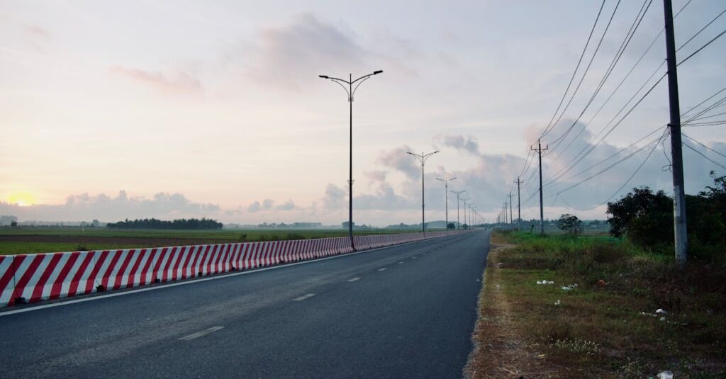 やわらかな朝焼けの中、遠くまで続く道。未来は跳ぶものではなく積み重ねの先にあることを象徴する風景。