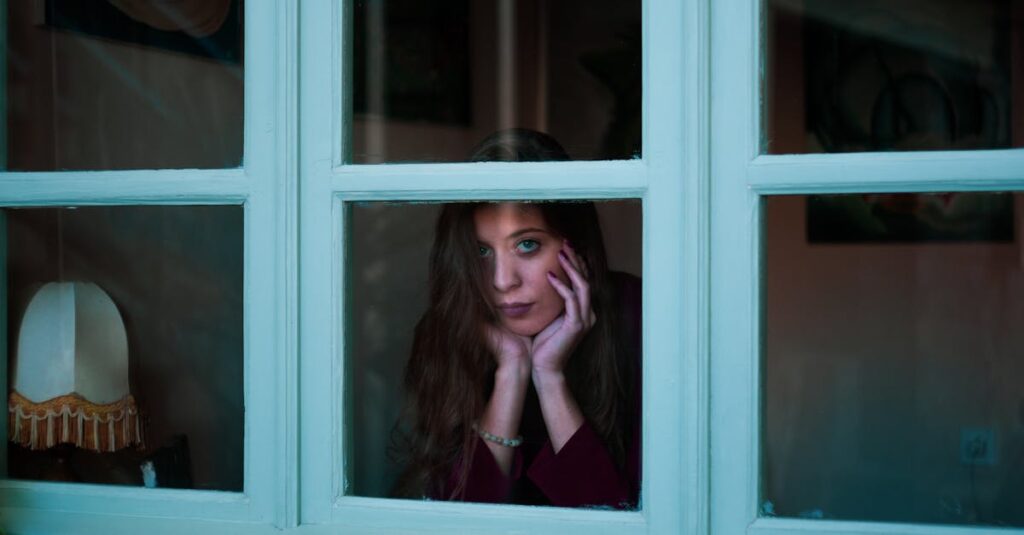 窓辺で静かに座り、感情と向き合う女性。我慢してきた日々を振り返る静かな時間。