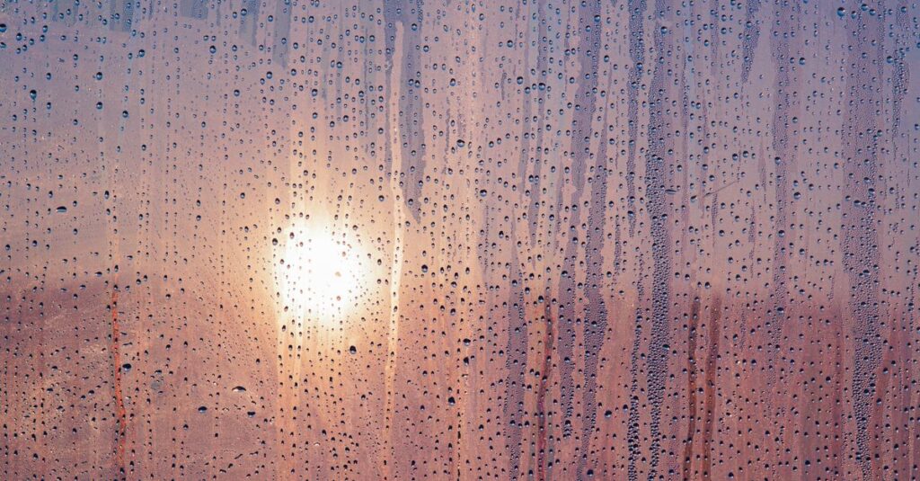 雨の日の窓辺で涙する女性。溜めてきた感情がそっとあふれる瞬間を象徴する風景。