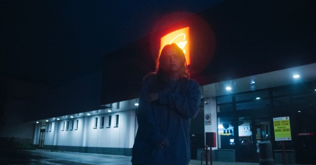 夜の街の光をひとり見つめる女性。未来の不安と静かに向き合いながら、自分の心の声を探している。
