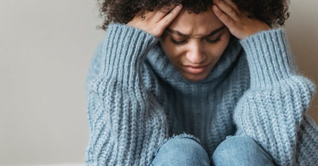 疲れた表情で静かに座る女性。愛されるための努力に消耗した日々を象徴する風景。