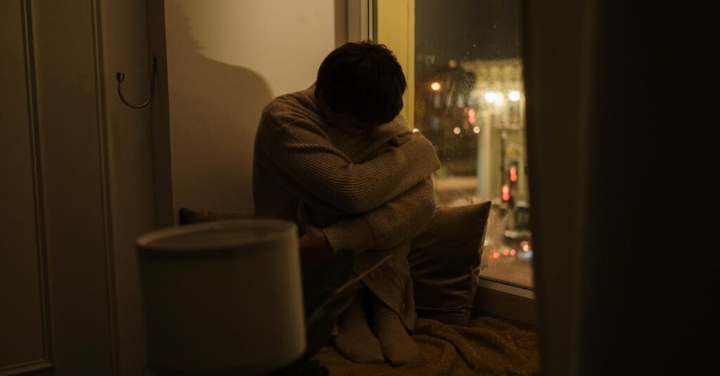 夜の静かな部屋で光を見つめる人。痛みの奥で、心はすでに回復を始めている。