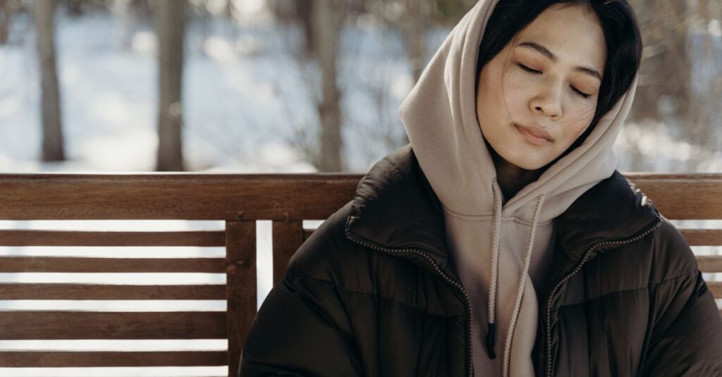 木陰のベンチでゆっくり休む女性。ちゃんとしなきゃを手放してゆるやかに生きる静かな自由を象徴する風景。