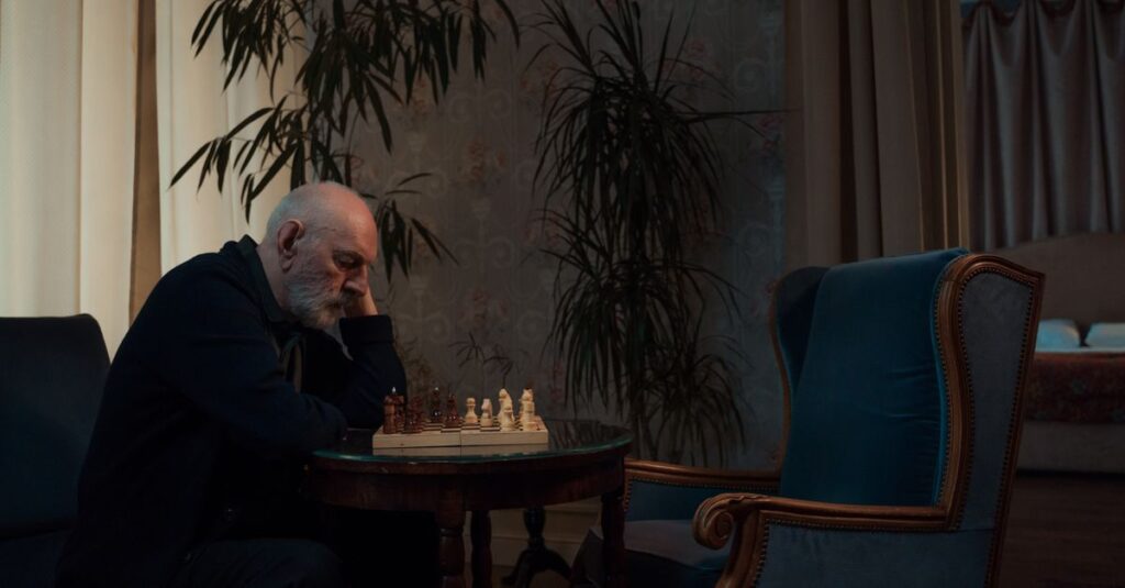 将棋盤の前で静かに座る青年。愛されるために頑張り続けた孤独を象徴する風景。