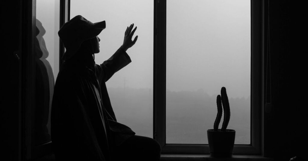 窓辺で静かに座り、感情と向き合う女性。我慢してきた日々を振り返る静かな時間。