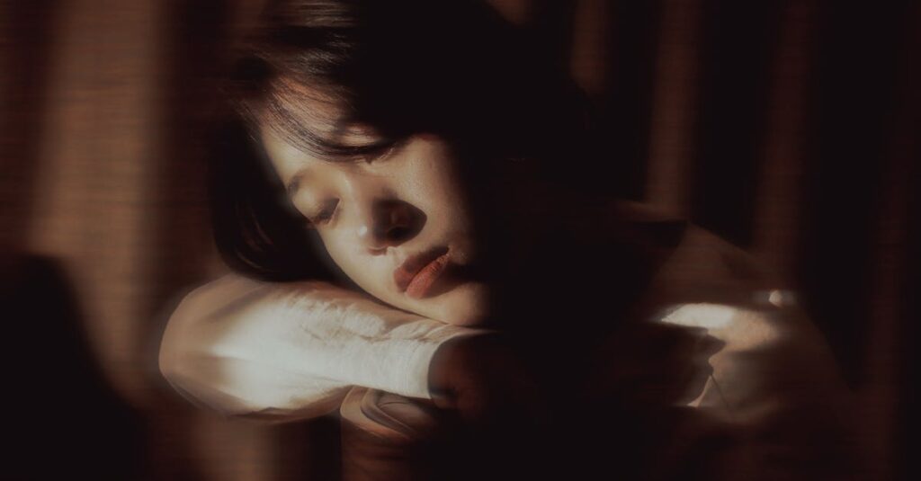 やわらかな光の中で静かに自分を抱きしめる女性。安心を求めて頑張ってきた日々を象徴する風景。