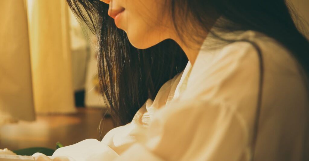 やわらかな光の中で静かに自分を抱きしめる女性。安心を求めて頑張ってきた日々を象徴する風景。