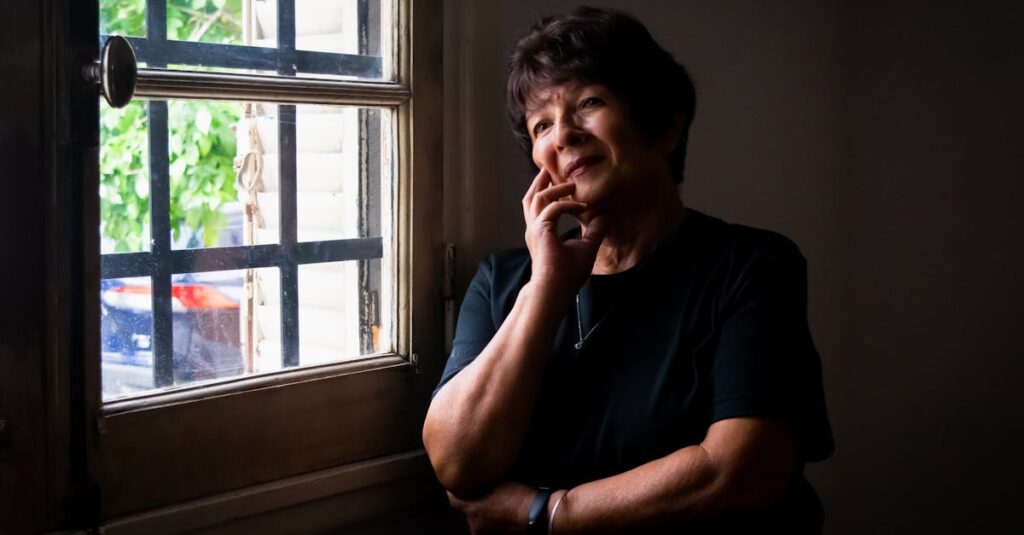 窓辺でひとり静かに外を見つめる女性。ひとりの時間に、自分の声がそっと戻ってくる。