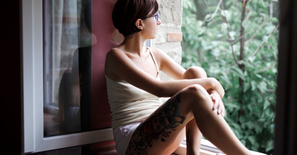 窓辺でひとり静かに外を見つめる女性。ひとりの時間に、自分の声がそっと戻ってくる。