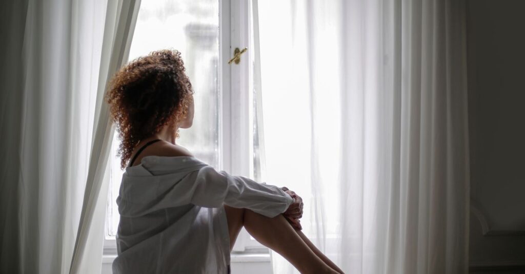 woman alone quiet room soft light holding back asking for help gentle calm
