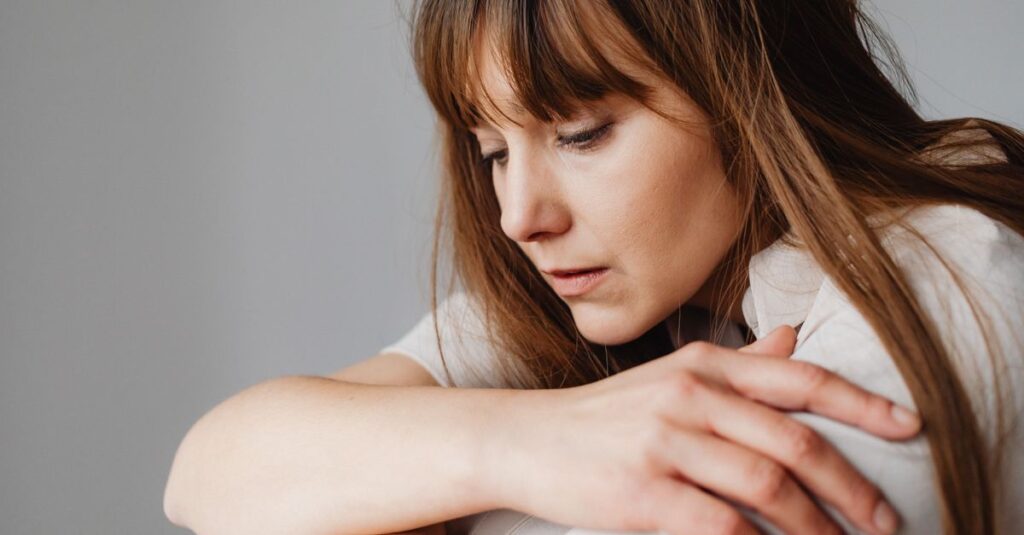 woman alone quiet room soft light holding back asking for help gentle calm